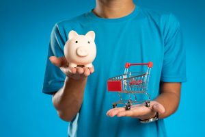 Man holding 'piggy bank' and miniature shopping trolley